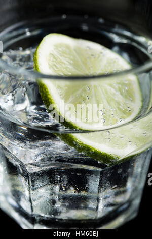 Il gin tonic cocktail con calce su sfondo nero Foto Stock