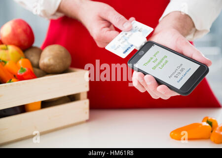 Uomo di ricarica per ortaggi utilizzando la carta di credito e lo smartphone Foto Stock