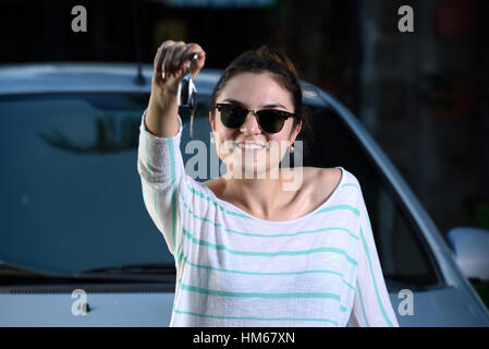 Ragazza giovane tenere premuto il tasto delle moderne auto grigio Foto Stock