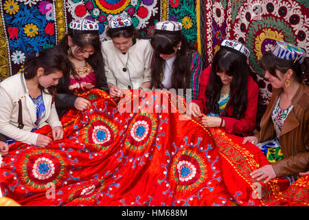 Ragazze tagike ricamare bellissimo tappeto in Central Park Navruzgoh durante la celebrazione del Nowruz (Nuovo Anno) nella città di Khujand Foto Stock