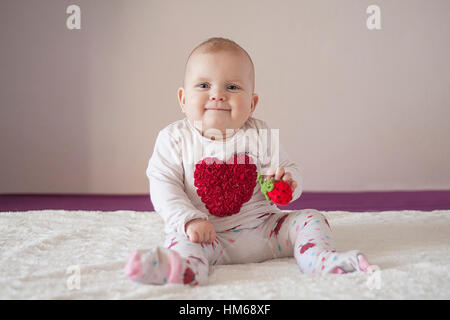 Sorridente bambina con cuore sul suo t-shirt e fragola nelle sue mani. Bianco sullo sfondo luminoso. Foto Stock