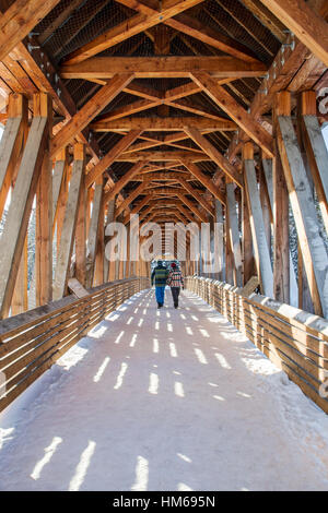 Uomo e donna attraversando Kicking Horse ponte pedonale oltre il Fiume Kicking Horse; GOLDEN; British Columbia; Canada Foto Stock