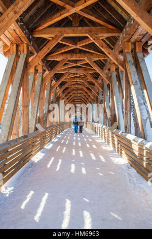 Uomo e donna attraversando Kicking Horse ponte pedonale oltre il Fiume Kicking Horse; GOLDEN; British Columbia; Canada Foto Stock