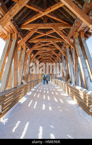 Uomo e donna attraversando Kicking Horse ponte pedonale oltre il Fiume Kicking Horse; GOLDEN; British Columbia; Canada Foto Stock