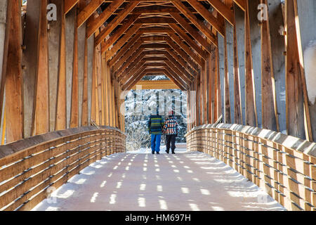 Uomo e donna attraversando Kicking Horse ponte pedonale oltre il Fiume Kicking Horse; GOLDEN; British Columbia; Canada Foto Stock