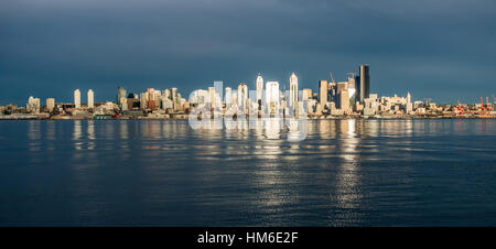 Come il sole tramonta edifici della skyline di Seattle sono riflesse nella Baia di Elliott. Foto Stock