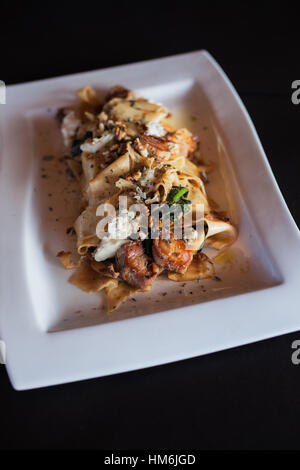 Pasta con carne di pollo nel piatto orizzontale con sfondo nero Foto Stock