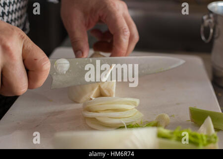 Chef di taglio Le cipolle crudo su una lavagna bianca Foto Stock