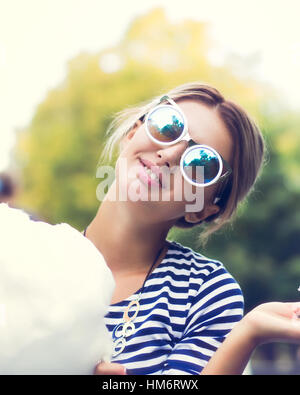 Ragazza adolescente mangiando caramelle di cotone in un parco della città Foto Stock