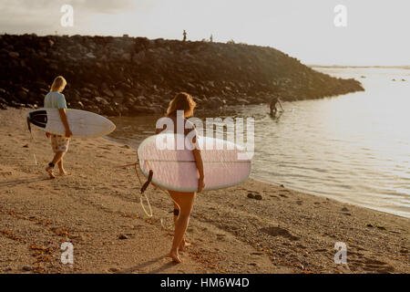 Amici con tavole da surf passeggiate in riva al mare Foto Stock