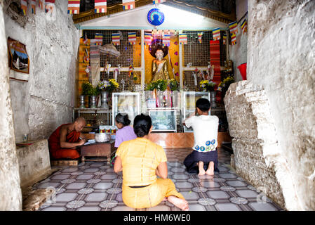 Interno del santuario Mingun Pahtodawgyi Mingun Myanmar | MINGUN, Myanmar — I devoti si inginocchiano davanti a un'immagine dorata di Buddha in una camera del santuario all'interno di Mingun Pahtodawgyi, lo stupa di mattoni incompiuto che il re Bodawpaya iniziò nel 1790. Sebbene il monumento non sia mai arrivato oltre i circa 164 piedi (50 m) del suo progetto di 492 piedi (150 m), le sue camere interne rimangono luoghi attivi di devozione buddista, curati oggi da monaci residenti. Foto Stock