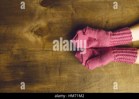 Il aperto della ragazza vestita di palme in rosa muffole. Le mani sono situati su un sfondo di legno. Posto per il testo Foto Stock