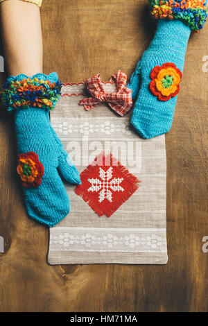 Pacchetto regalo di artigianato che si trova su un sfondo di legno. Il pacchetto contiene è in la ragazza in mani che sono vestiti in blu mittens Foto Stock