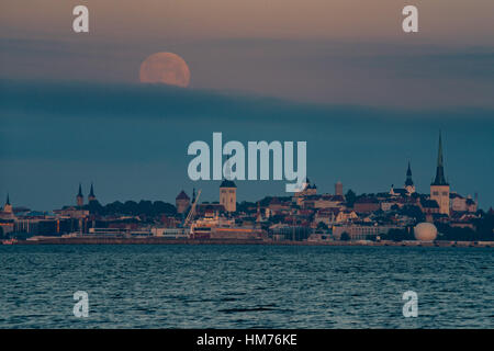 Luna piena oltre il centro storico della città di Tallinn, Estonia. Luna tramonta prima del sorgere del sole Foto Stock