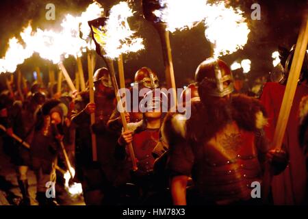 I membri della squadra Jarl vestito in costumi Viking portano torce fiammeggianti durante la Up Helly Aa Viking Festival di Lerwick sulle Isole Shetland. Foto Stock