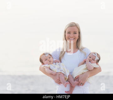 Ritratto di felice metà adulto madre portante due ragazze baby (2-5 mesi) Foto Stock