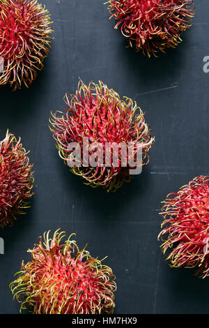 Rambutan (Nephelium lappaceum) frutti sulla superficie grigia Foto Stock