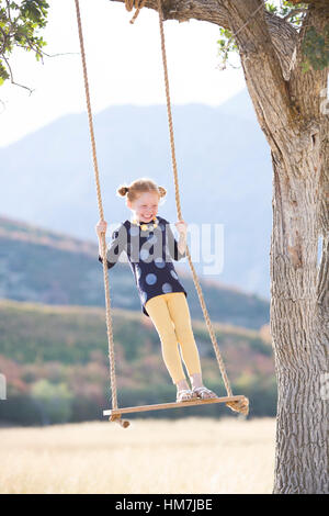 La ragazza (4-5) in piedi su swing Foto Stock