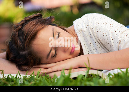 Ragazza dormire con libro su erba verde park Foto Stock