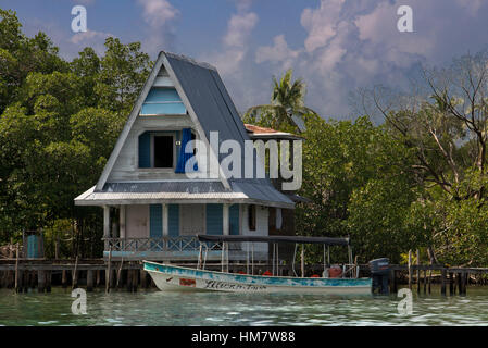 Casa su palafitte sopra l'acqua con i pannelli solari e la fitta vegetazione tropicale in background, Bocas del Toro, Mar dei Caraibi, Panama. Cabina tropicale su t Foto Stock