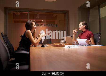 Femmina di due colleghi di lavoro che lavora fino a tardi in un ufficio Foto Stock
