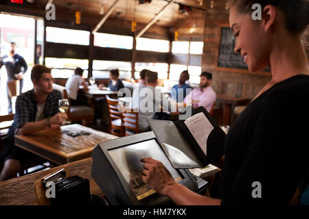 Giovane donna la preparazione di bill al ristorante con touch screen Foto Stock