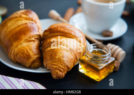 Cornetti freschi con vaso di miele e caffè, sala colazione, il fuoco selettivo Foto Stock