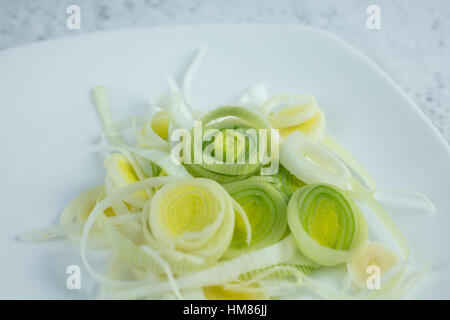 I porri tagliati a fettine sottili anelli su una piastra bianca ad essere utilizzato per un ingrediente Foto Stock