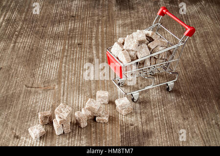 Carrello marrone con zucchero di canna su sfondo di legno Foto Stock