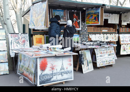 I turisti sfoglia stampa stallo del mercato lungo il Fiume Senna a Parigi in inverno Foto Stock