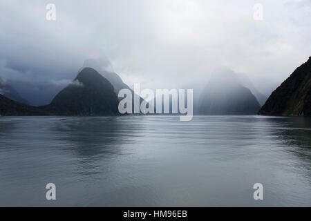 Visualizza in basso rainswept Milford Sound, montagne oscurate dal cloud, Milford Sound, Parco Nazionale di Fiordland, Southland, Nuova Zelanda Foto Stock