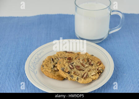 Freschi di forno chocolate chip cookies alle noci pecan su una piastra bianca su un posto blu mat. Stati Uniti d'America. Foto Stock