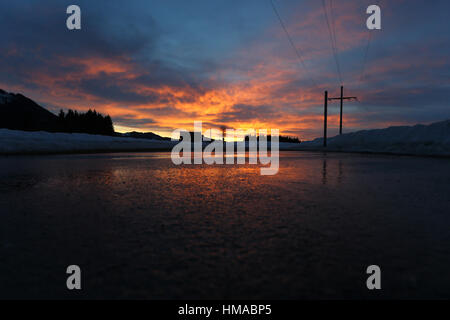 Wertach, Germania. 02Feb, 2017. Il cielo colorfully illuminato dal sole al tramonto che si riflette in una strada coperta di neve vicino a fusione Wertach, Germania, 02 febbraio 2017. Foto: Karl-Josef Hildenbrand/dpa/Alamy Live News Foto Stock