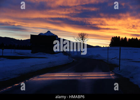 Wertach, Germania. 02Feb, 2017. Il cielo colorfully illuminato dal sole al tramonto che si riflette in una strada coperta di neve vicino a fusione Wertach, Germania, 02 febbraio 2017. Foto: Karl-Josef Hildenbrand/dpa/Alamy Live News Foto Stock