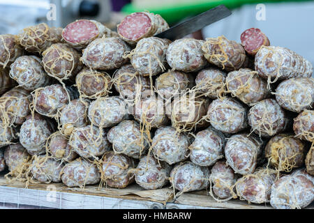 Ordinatamente accatastato francese salsiccia secca (saucisson) su uno stallo del mercato a Saint-Palais-sur-Mer, Charente-Maritime, sulla costa sud-occidentale della Francia. Foto Stock