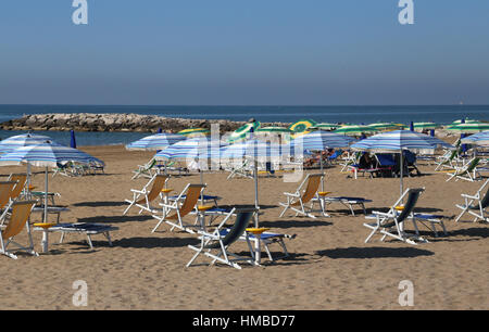 Molti ombrelloni e sedie a sdraio in spiaggia assolata in estate Foto Stock