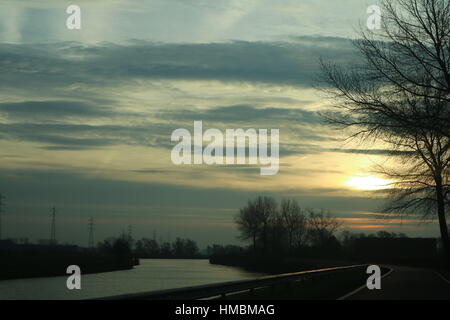 Sun dietro le nuvole riflettendo sull'acqua Foto Stock