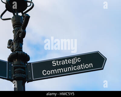Illuminazione stradale pole con messaggio concettuale comunicazione strategica sulla freccia direzionale blu su sfondo nuvoloso. Foto Stock