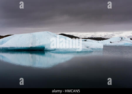 Iceberg galleggianti in Jökulsárlón laguna glaciale contro un buio cielo tempestoso Foto Stock