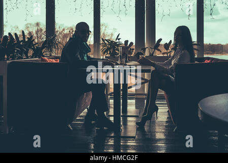 La silhouette dell'amore giovane seduto in cafe Foto Stock