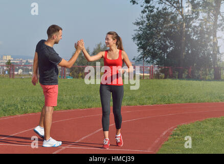 Montare la giovane donna dando alta cinque per il suo fidanzato dopo una corsa. Un sano concetto di fitness con uno stile di vita attivo. Foto Stock