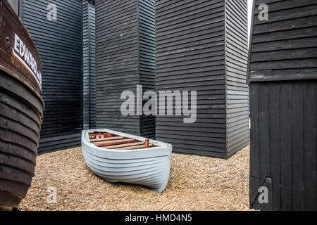 Hastings, Inghilterra - Dicembre 30, 2016: barca bianca e la vecchia fishermans capanne di legno sul lungomare di Hastings old town, East Sussex, England, Regno Unito Foto Stock