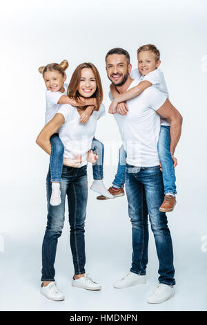 Piggybacking i genitori dei bambini felici Foto Stock