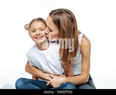 Madre abbracciando e baciando figlia sorridente Foto Stock