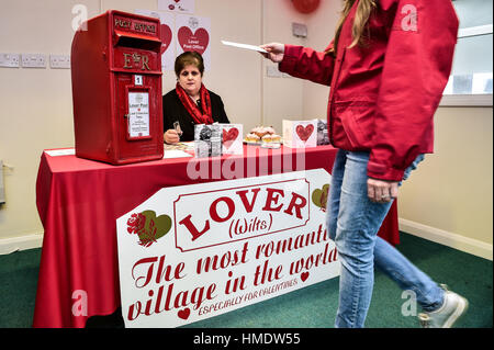 Una donna posti un il giorno di San Valentino scheda nella finestra pop-up post office nel villaggio di Amante, nuova foresta dove i residenti hanno lanciato un il giorno di San Valentino post service, consentendo ai romantici in tutto il mondo per inviare una scheda da Wiltshire village. Foto Stock