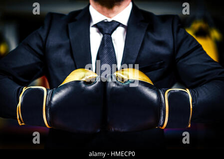 Imprenditore con i guantoni è pronto per la battaglia aziendale. Uomo in tuta, camicia e cravatta è azienda guanti combat insieme. Girato in una palestra di inscatolamento, co Foto Stock