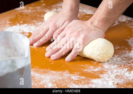 L'uomo impastare la pasta su una farina coperti da tavola Foto Stock