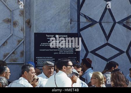 Scena di Western di uomini e donne ai turisti in attesa di entrare in moschea in cima al monte del tempio, nella Città Vecchia di Gerusalemme, Israele, novembre 1967. La polizia israeliana cartello di avviso in lingua inglese, arabo ed ebraico incarica i visitatori a comportarsi in modo appropriato al sito religioso. (Foto dalla collezione di Morse/Gado/Getty Images). Foto Stock