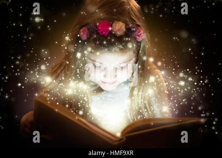 Bellissima bambina la lettura di libro magico, il concetto di fantasia Foto Stock