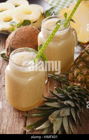 Cocktail di ananas e noce di cocco in un barattolo di vetro closeup sul piano verticale. Foto Stock